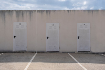 Three storage room doors against a blue sky. Simmetry in a minimalist background. Epmty copy space for Editor's content.