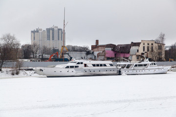 The pleasure motor ship in the winter parking is frozen into the ice