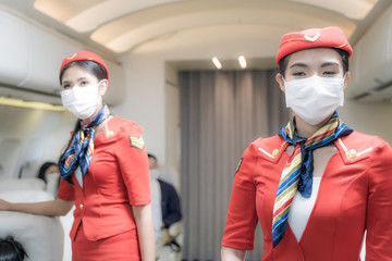 Asian woman air hostess or Flight attendant boarding plane standing in plane. people wearing face...