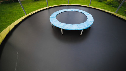 small trampoline on big one with round mat, size comparison, green lawn background