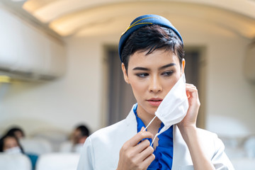 woman air hostess or Flight attendant boarding plane standing in plane and wearing face mask....