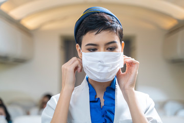 woman air hostess or Flight attendant boarding plane standing in plane and wearing face mask....