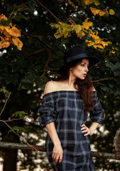 Beautiful sexy woman posing in blue dress and blue hat on summer day trees colors. Closeup fashion style