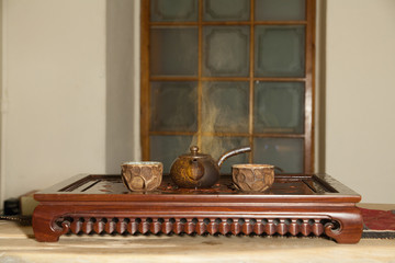 Chinese teapot and cups on a vintage wooden table among a cloud of brown steam