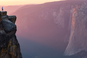 A hiker stands at the edge of a cliff at Taft Point overlooking El Capitan in Yosemite National Park, California © Michael Carni