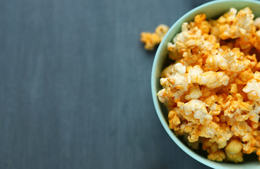 Delicious cheese popcorn in a blue dish on a gray background. Selective focus. Space for text. Copy space