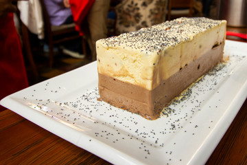 Refreshing cream ice cream with nuts and chocolate, served piece on plate.