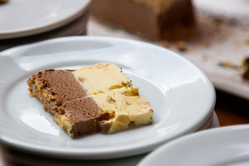 Refreshing cream ice cream with nuts and chocolate, served piece on plate.