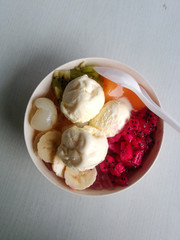 fruit bowl with vanilla ice cream topping on a white bowl. on a white table background. flatlay photo