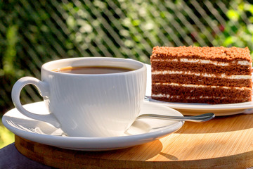 A cup of black coffee with a delicious sweet dessert on a wooden stand.