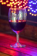 red wine glass against christmas lights decoration background, christmas atmosphere