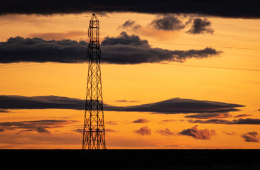 gran antena de trasmision en contraste al atardecer anaranjado con nubes negras 