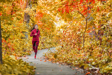 Autumn forest run path. Fall trail runner woman running in beautiful foliage woods nature background. Asian happy sports woman training outdoor. Active lifestyle girl jogging exercise.