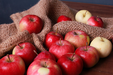 Red apples on burlap sackcloth on brown wooden board. Closeup view. Natural organic food, agriculture, horticulture, harvest season concept