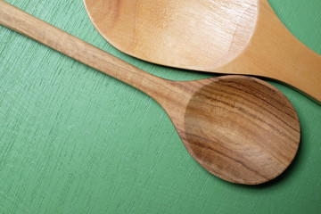 Wooden spoon on a green wooden background.