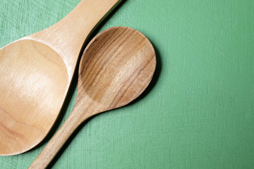 Wooden spoon on a green wooden background.
