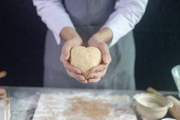 Chef showing buns dough heart shape in his hands, Homemade bakery concept
