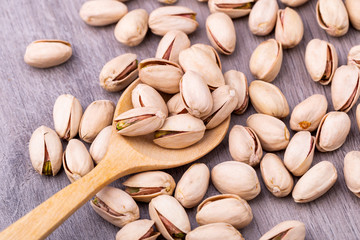 Pistachio in a wooden spoon on grained wood background.