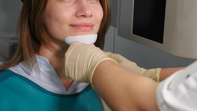 Doctor radiologist in dental clinic adjusting female patient head before MRI procedure. Dental scanning. Young pleasant woman undergoing tests on dental X-Ray scanner. 4 k video