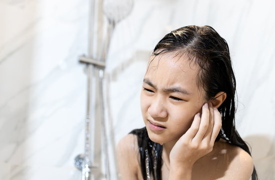 Stressed Worried Asian Child Girl Had Tinnitus Water In Her Ear Canal While Washing Her Hair,female Cleaning Her Ear While Taking A Shower Under Flowing Water In The Bathroom,swimmer's Ear Concept