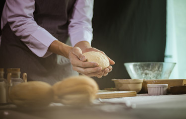 Obraz na płótnie Canvas Chef showing buns dough in his hands, Homemade bakery concept