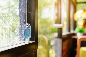 Blue alcohol gel bottle for hand cleaning to prevent the spreading of the Coronavirus (Covid-19), Placed on the windowsill with water drops in background. Healthcare concept. New normal lifestyle