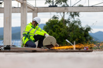 Asian senior worker cutting steel on the roof truss construction site