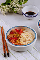 Chicken teriyaki with bell peppers, broccoli and noodles in bowl with chopsticks.