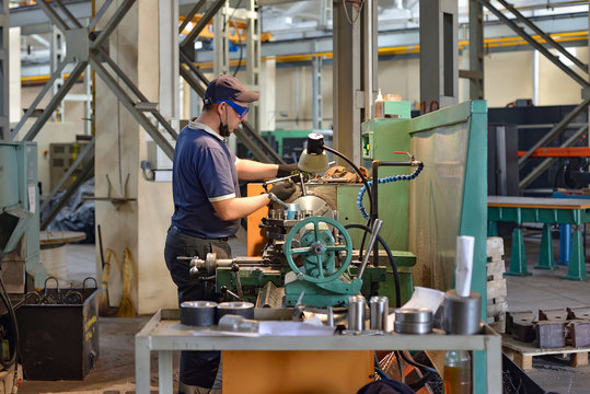 A working turner sets a part on a lathe.