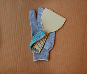 Renovation tools: building spatula on working glove on brown cardboard. Flat lay