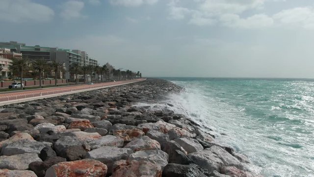 A road along the coastline fortified with stones in Dubai, filmed by drone on clody day