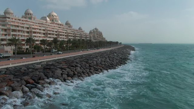 A road along the coastline fortified with stones in Dubai, filmed by drone on clody day
