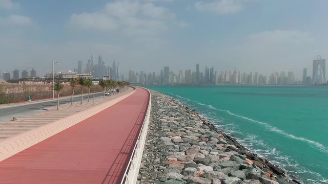 A road along the coastline fortified with stones in Dubai, filmed by drone on clody day