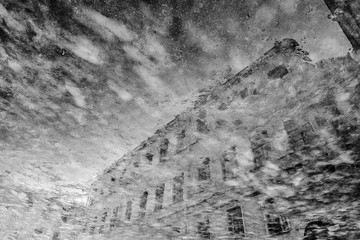 Facade of a vintage residential building reflected in a freezing puddle
