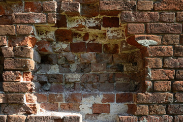Close-up section of the old brickwork of a red brick wall, part of the wall in the center of the frame is destroyed.