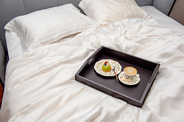 Tray with coffee in a large bed in the morning on a bed linen