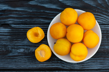 The yellow plum lies on a white plate on a dark wooden table.