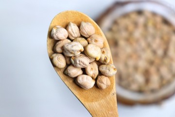 Uncooked dried Chickpeas in a wooden bowl on white background. Preparation for making a hummus dish.High protein ingredient with copy space.  