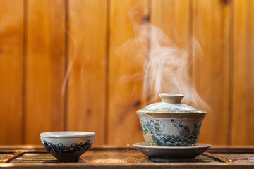 Cup of chinese tea with cloud of steam on wooden background