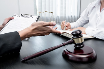 A male lawyer or a judge counseling clients about judicial justice and prosecution with scales, judges gavel, legal documents legal services concept