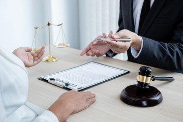 A male lawyer or a judge counseling clients about judicial justice and prosecution with scales, judges gavel, legal documents legal services concept