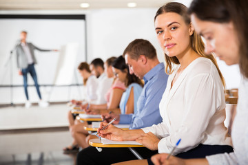 Side view of intelligent girl sitting with her fellow students in auditorium during classes