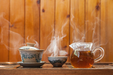 Chinese tea cup and glass kettle  with cloud of vapor on wooden background