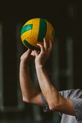Volleyball player hands squeeze striped ball from above
