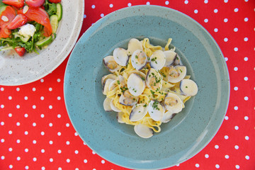 Served table at summer terrace cafe. Salmon salad and pasta with clams. Eating out in restaurant, summer terrace.
