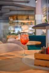 A glass with the red citrus cocktail. Alcohol summer beverage in a wine glass. Refreshing drink with ice.