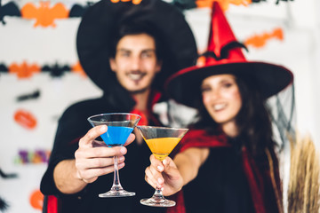 Couple having fun holding pumpkins and wearing dressed carnival halloween costumes and makeup posing with bats and balloons on background at the halloween party.Halloween holiday celebration concept