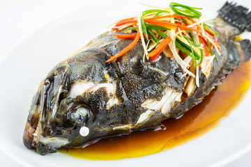 A dish of Cantonese steamed grouper on white background