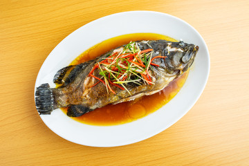 A dish of Cantonese steamed grouper on wooden table