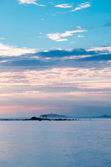 Light ray over the sea with the view of torii gate and light house in the distance. Portrait orientation.